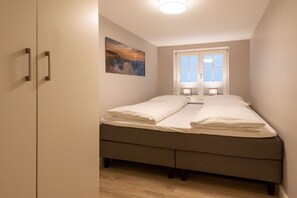 A bedroom with a bed, a window, and a painting on the wall.