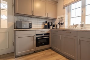 A modern kitchen with light-colored cabinets, a microwave, coffee maker, and a fish-shaped soap holder. - Achter Dünem, Whg. 4 - Strandnahe 3-zimmer Ferienwohnung auf 70 m² Wohnfläche, für bis zu 4 Personen (Wenningstedt-Braderup (Sylt))