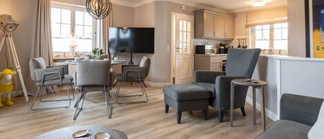 A modern living room with a sofa, chairs, a dining table, and a kitchen in the background.