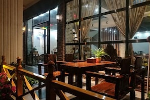 A restaurant with a wooden dining area, large windows, and a view of the street. - Dongxing Jinghui Hotel (Dongxing)