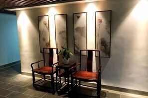 A seating area with a table and chairs, a potted plant, and artwork on the wall. - Dongxing Jinghui Hotel (Dongxing)