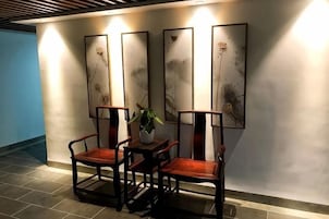 Un área de estar con una mesa y sillas, una planta en maceta y obras de arte en la pared.