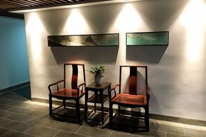 A seating area with two chairs and a small table, a potted plant, and two wall-mounted artworks. - Dongxing Jinghui Hotel (Dongxing)