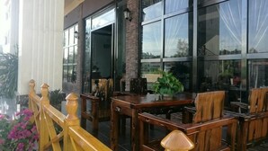 A patio area with wooden furniture, large windows, and a view of the outdoors.