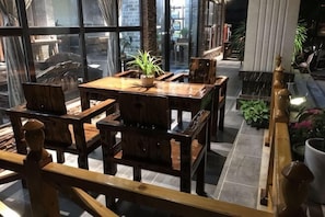 A wooden dining area with tables and chairs, potted plants, and a view through large windows. - Dongxing Jinghui Hotel (Dongxing)