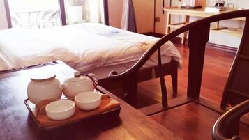 Een hotelkamer met een bed, een houten tafel met theepotten en kopjes, en uitzicht op buiten.