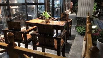 A wooden dining area with a table and chairs, a potted plant, and a view through large windows.