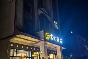 Un hotel con un letrero iluminado llamativo, un balcón y vistas de los edificios circundantes.