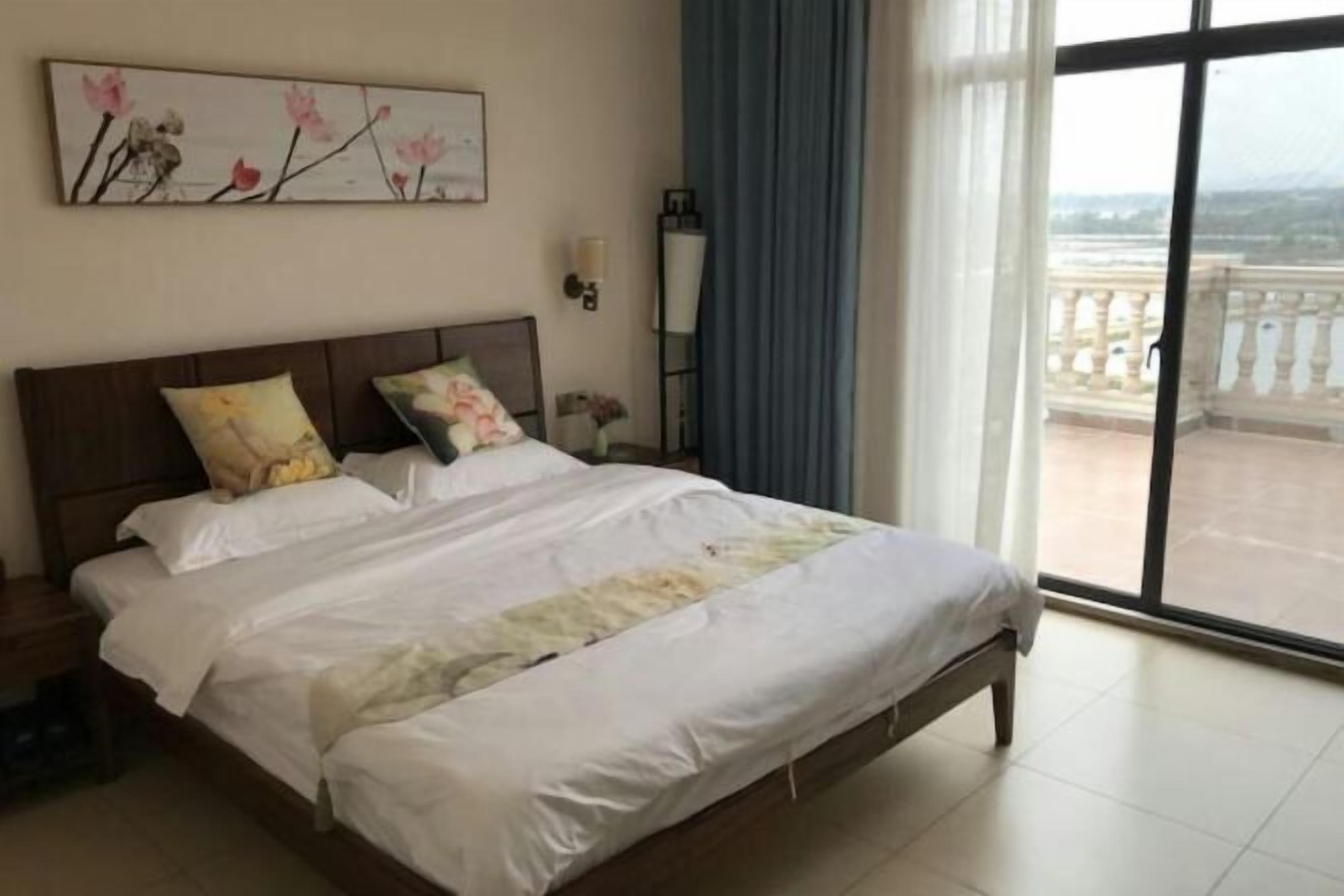Een hotelkamer met een groot bed, een nachtkastje, een wandlamp en uitzicht op een balkon.
