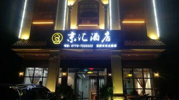 A hotel entrance with illuminated signage, a visible reception desk, and a car parked in front.