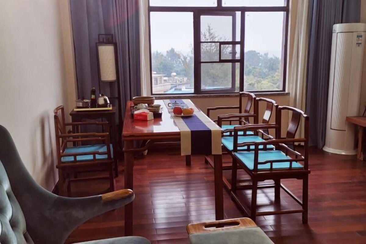 Un comedor con una mesa larga, sillas de madera y vistas a través de una ventana.
