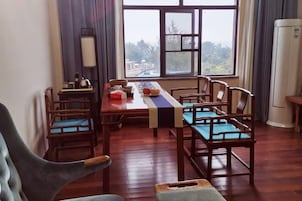 Uma área de refeições com uma mesa comprida, cadeiras de madeira e vista pela janela.