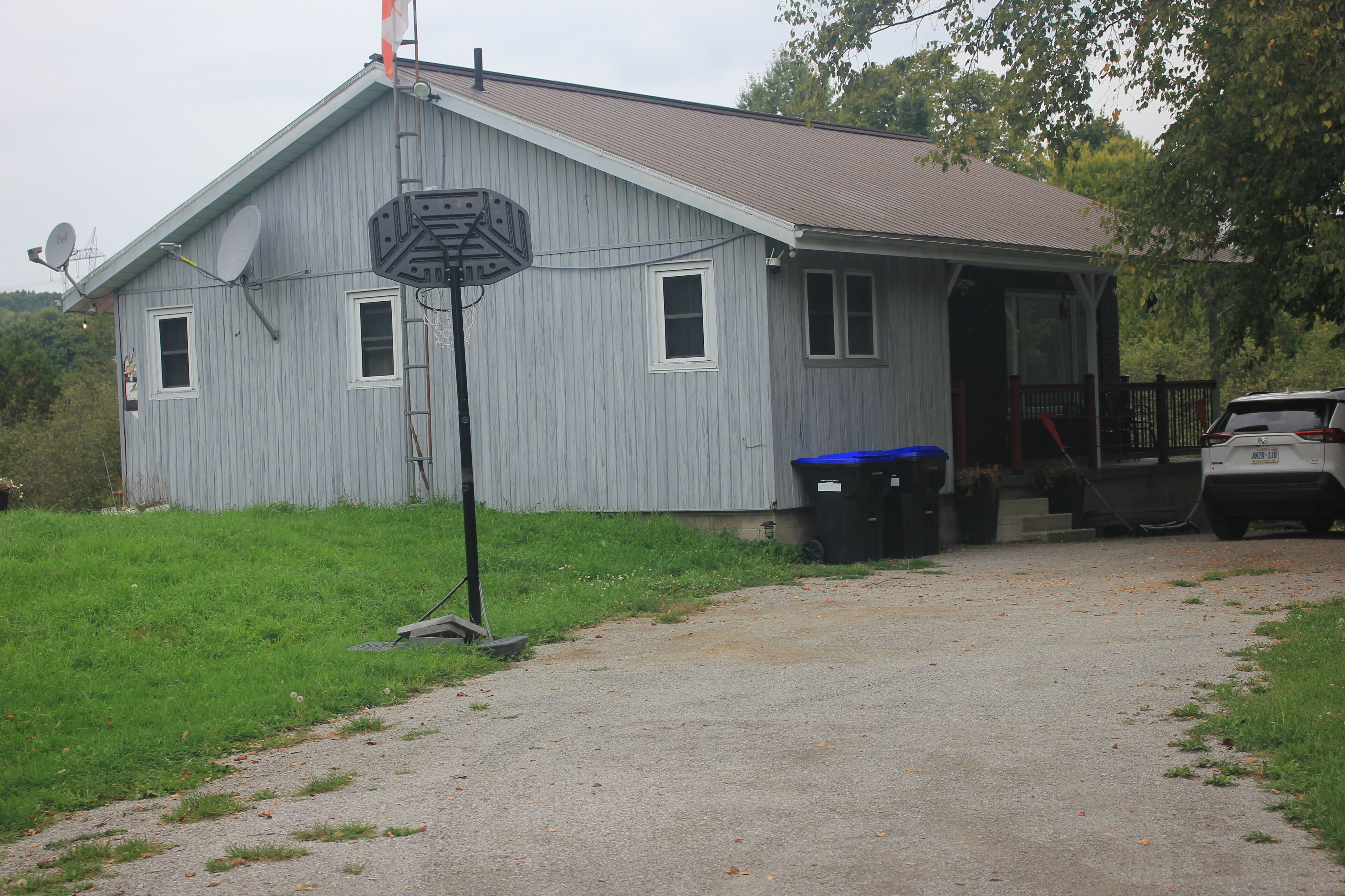 A single-story building with a sloped roof, a front porch, and a satellite dish.