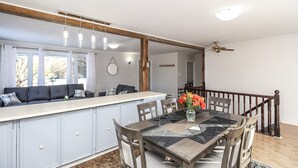 Eine moderne Küche mit Essbereich, ausgestattet mit einer großen Kochinsel, Holzstühlen und einem Deckenventilator.