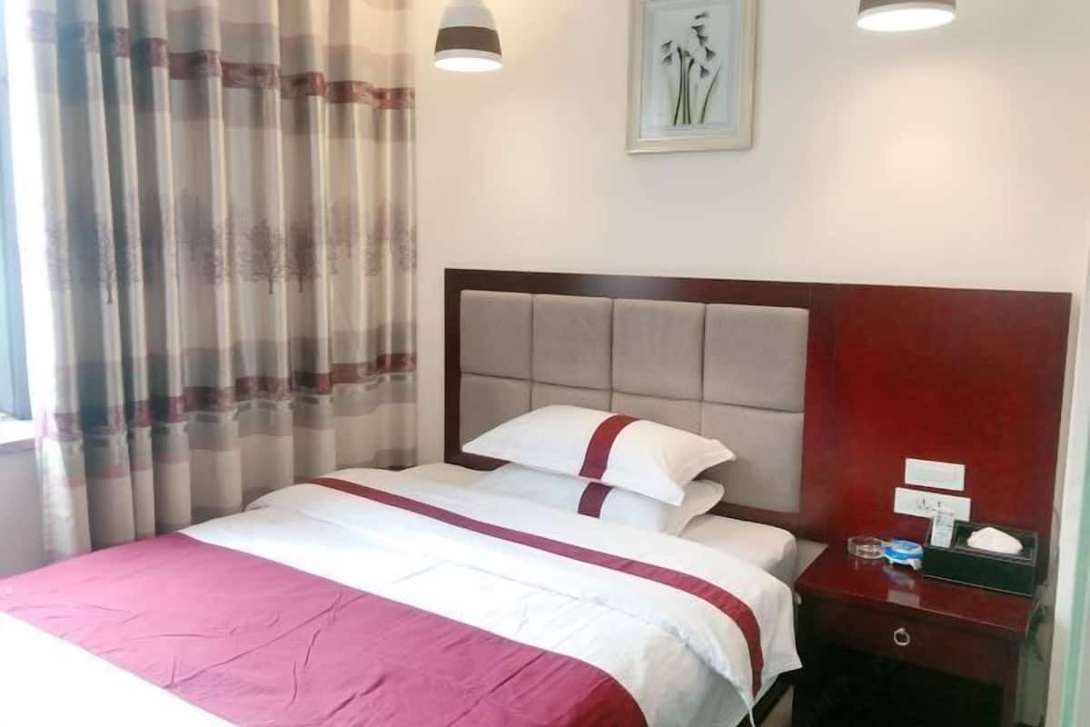 Quarto de hotel com cama, mesa de cabeceira, luminária e um quadro pendurado na parede.