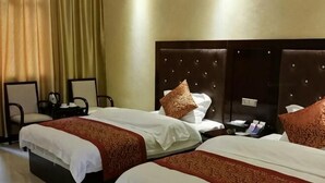 Een hotelkamer met twee bedden, een nachtkastje, een stoel en een groot raam met gordijnen.