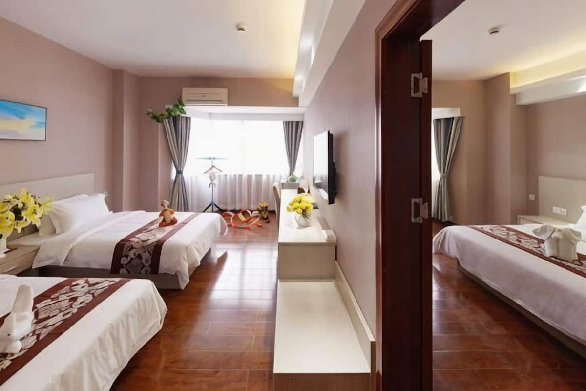 Quarto de hotel com duas camas, uma escrivaninha, uma cadeira, uma televisão e uma janela com cortinas.