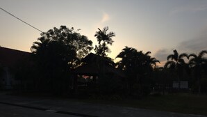 A building with a red-tiled roof, surrounded by palm trees and a grassy area. - Maingam Resort (Si Prachan)