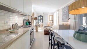 A modern kitchen with white cabinets, a dining area with a table and chairs, and a large window with curtains. - Porto Letizia Viola 1, Porlezza, Italy (Porlezza)