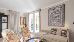 A living room with a sofa, two wicker chairs, a coffee table with a cup and cookies, a bookshelf, and a large framed artwork on the wall. - Porto Letizia Viola 1, Porlezza, Italy (Porlezza)