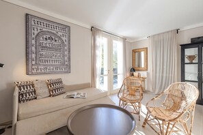 A room with a sofa, two wicker chairs, a round table, a large framed artwork, and a cabinet with a mirror. - Porto Letizia Viola 2, Porlezza, Italy (Porlezza)