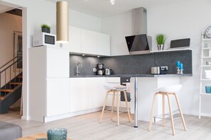 Una cocina moderna con armarios blancos, encimera negra y dos taburetes de madera.