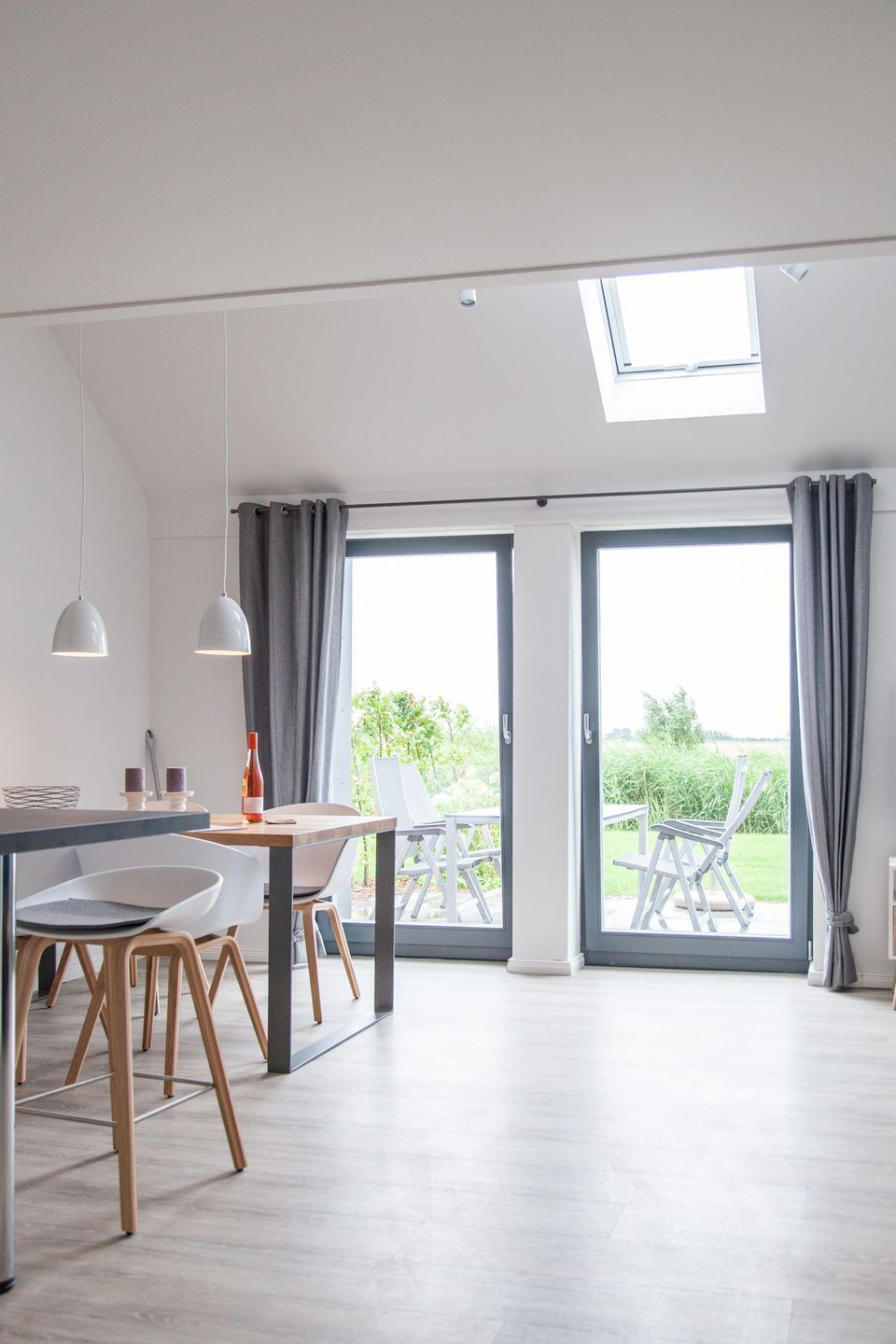 A modern kitchen with a dining area, large windows, and a skylight.