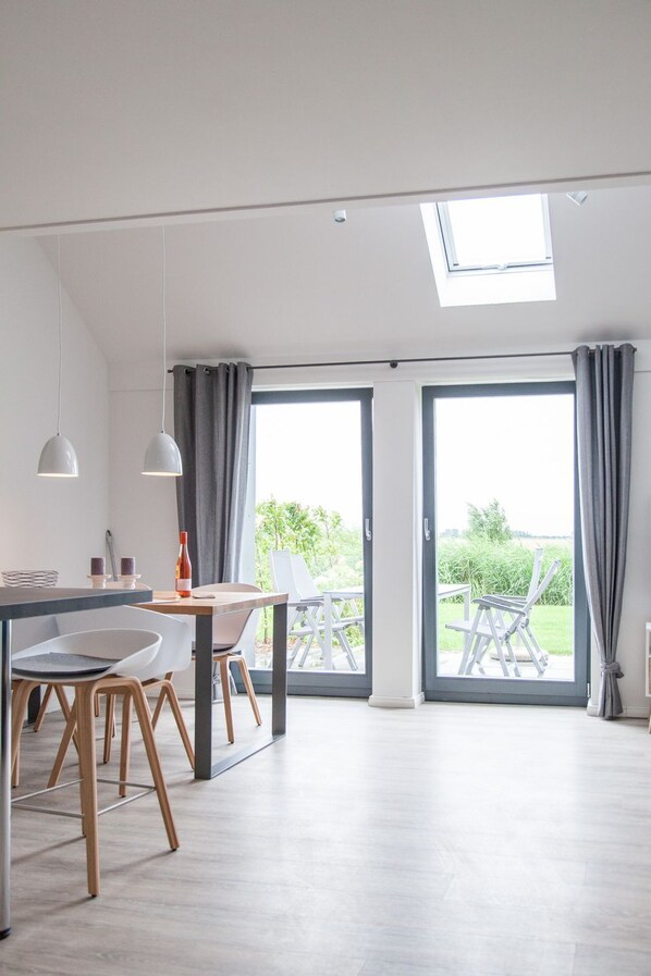A modern kitchen with a dining area, large windows, and a skylight.