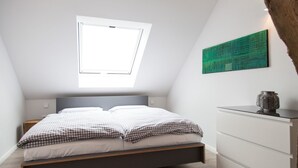 Un dormitorio con cama, ventana, una obra de arte verde y un aparador.