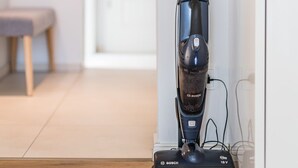 Un aspirador en una cocina con piso de madera y armarios blancos.