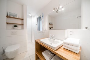 Ein modernes Badezimmer mit einem Holzwaschtisch, weißen Armaturen und einem großen Spiegel.
