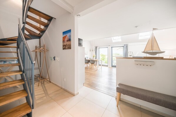 A modern interior with a wooden staircase, a dining area, and a bench.