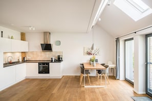 Una cocina moderna con zona de comedor, suelo de madera y tragaluz.