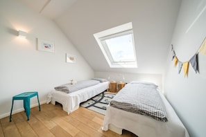Una habitación pequeña y luminosa con dos camas individuales, una ventana y un tragaluz.