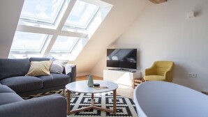En moderne stue med sofa, en gul lænestol, sofabord og fjernsyn.
