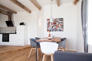 Moderni keittiö, jossa on valkoiset kaapit, sisäänrakennettu uuni ja puinen katto.
