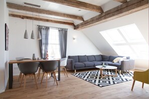 Ein Loft-Wohnraum mit Essbereich, einem grauen Sofa und einem gelben Sessel.