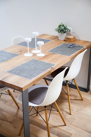 Ein Holzespeisetisch mit vier weißen Stühlen, grauen Platzsets und weißen Kerzenständern.
