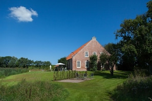 A brick house with a red roof, surrounded by a well-maintained lawn and trees.