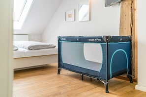 A room with a loft bed, a small trampoline, and a wooden floor.