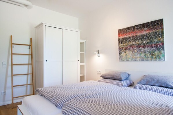 Une chambre à coucher comprenant un lit, une armoire, une échelle et un luminaire fixé au mur.