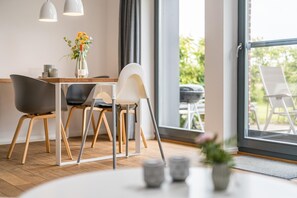 Un área de comedor moderna con una mesa de madera, dos sillas y un jarrón con flores.