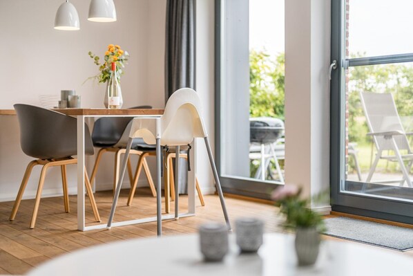 Un espace repas moderne avec une table en bois, deux chaises et un vase rempli de fleurs.