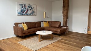 Ein modernes Wohnzimmer mit einem braunen Leder-Modulsitz, einem runden Couchtisch und einem großen, abstrakten Gemälde an der Wand.