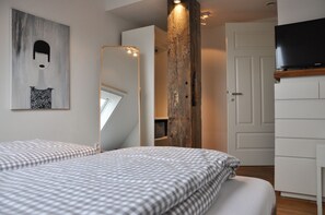 Ein Schlafzimmer mit einem großen Spiegel, einem Bett mit karierter Bettwäsche, einer Holzsäule und einem Fernseher auf einem Tisch.