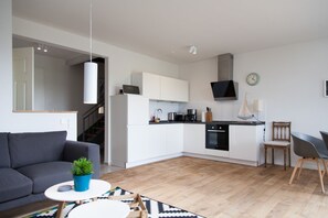 A modern apartment with a kitchen, living area, and a staircase.