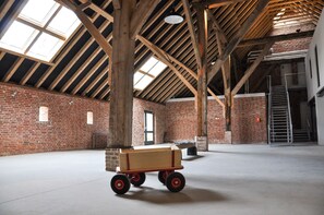 Un intérieur spacieux avec des poutres apparentes, des murs en briques et un plancher en béton.