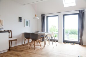 Et moderne spiseområde med et træbord, fire stole og en hængende pendellampe.
