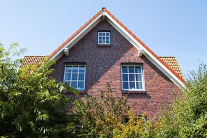 Ett hus byggt av rött tegel, med ett sadeltak och två fönster.