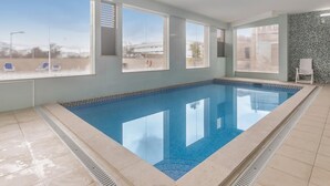Ein Schwimmbecken mit klarem, blauem Wasser, umgeben von hellblauen Wänden und großen Fenstern.